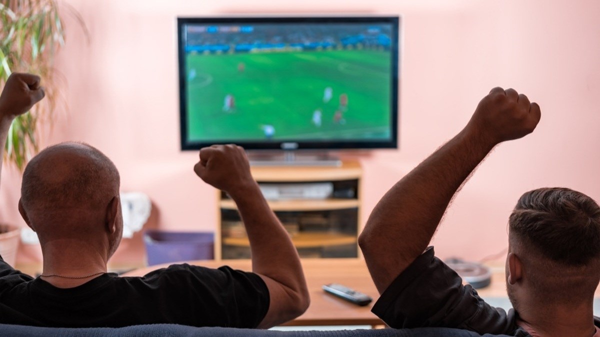 Dva fanoušci slaví gól při sledování fotbalu v televizi