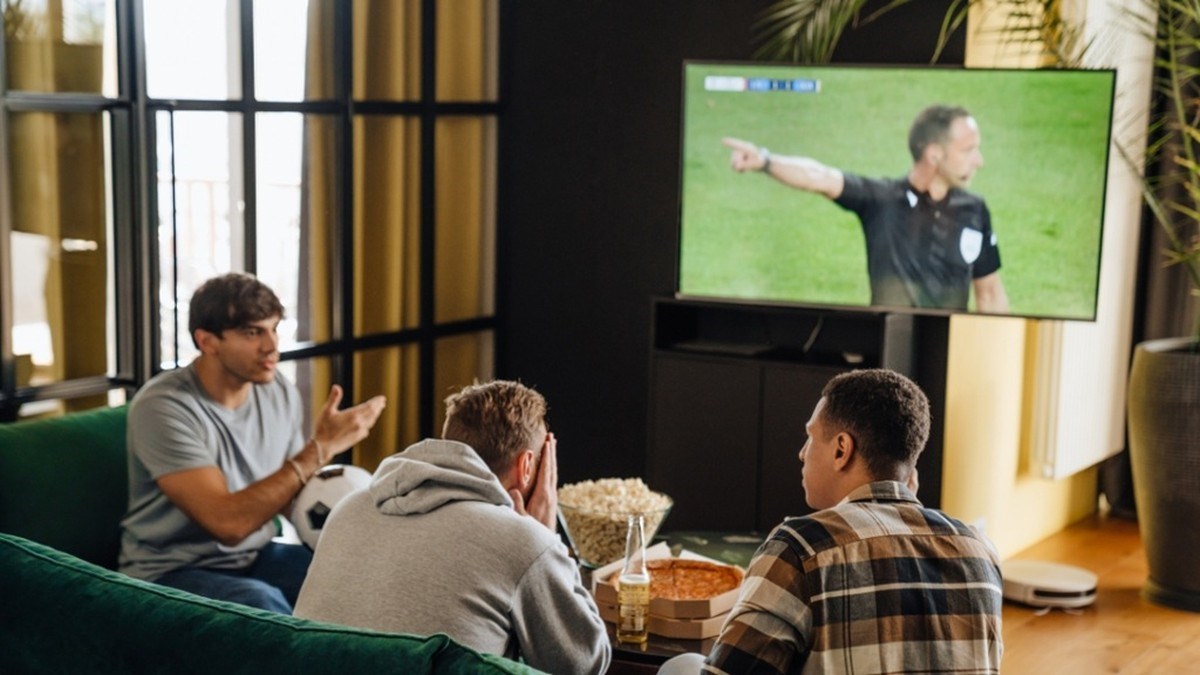 Přátelé sledují fotbal v televizi u občerstvení v obývacím pokoji