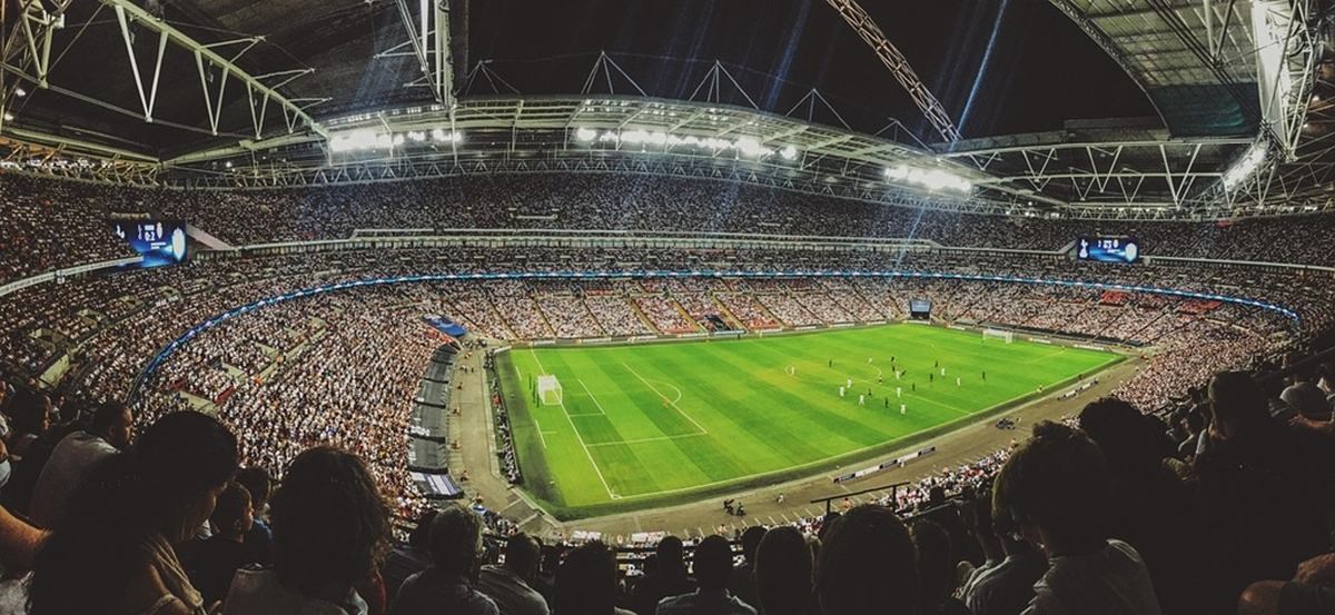 Zaplněný fotbalový stadion během večerního zápasu