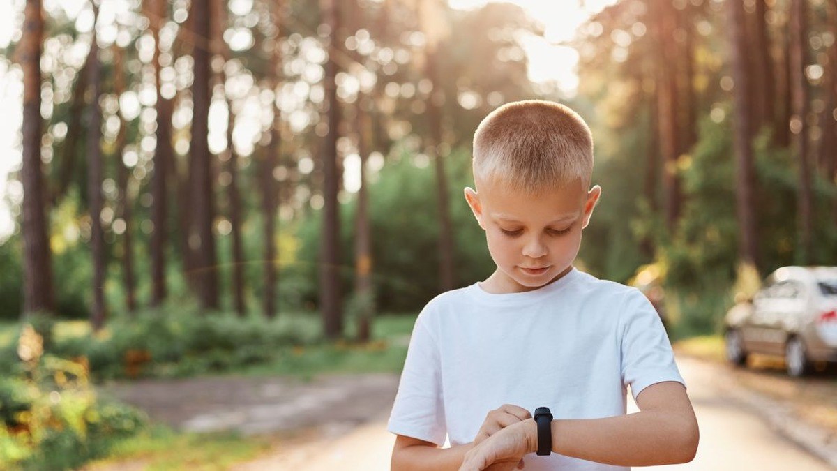 Chlapec kontroluje chytré hodinky venku v přírodě
