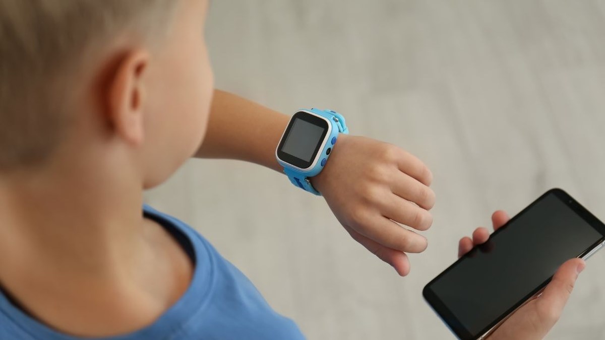 Dítě s chytrými hodinkami a rodičovskou aplikací v mobilu